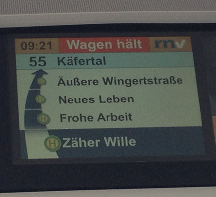 Photo of a stop display of bus number 55 in Mannheim, you can read the next three stops: "Zäher Wille" (tenacious will), "Frohe Arbeit" (happy work) and "Neues Leben" (new life).